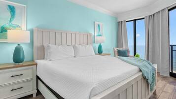 A hotel room with a bed, nightstands, a chair, a window with a view, and artwork on the walls.