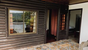 A log cabin interior with a large window, a patterned floor, and a door leading to another room. - Hotel Manglares (Caldera)