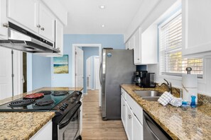 A modern kitchen with granite countertops, stainless steel appliances, and a view to the adjacent living area. - Sun and Sand (Panama City Beach)