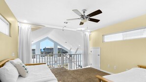 A bedroom with two beds, a ceiling fan, and a view of a balcony. - Sun and Sand (Panama City Beach)