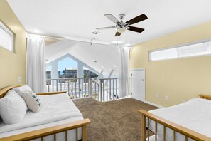 A bedroom with two beds, a ceiling fan, and a view of a balcony. - Sun and Sand (Panama City Beach)