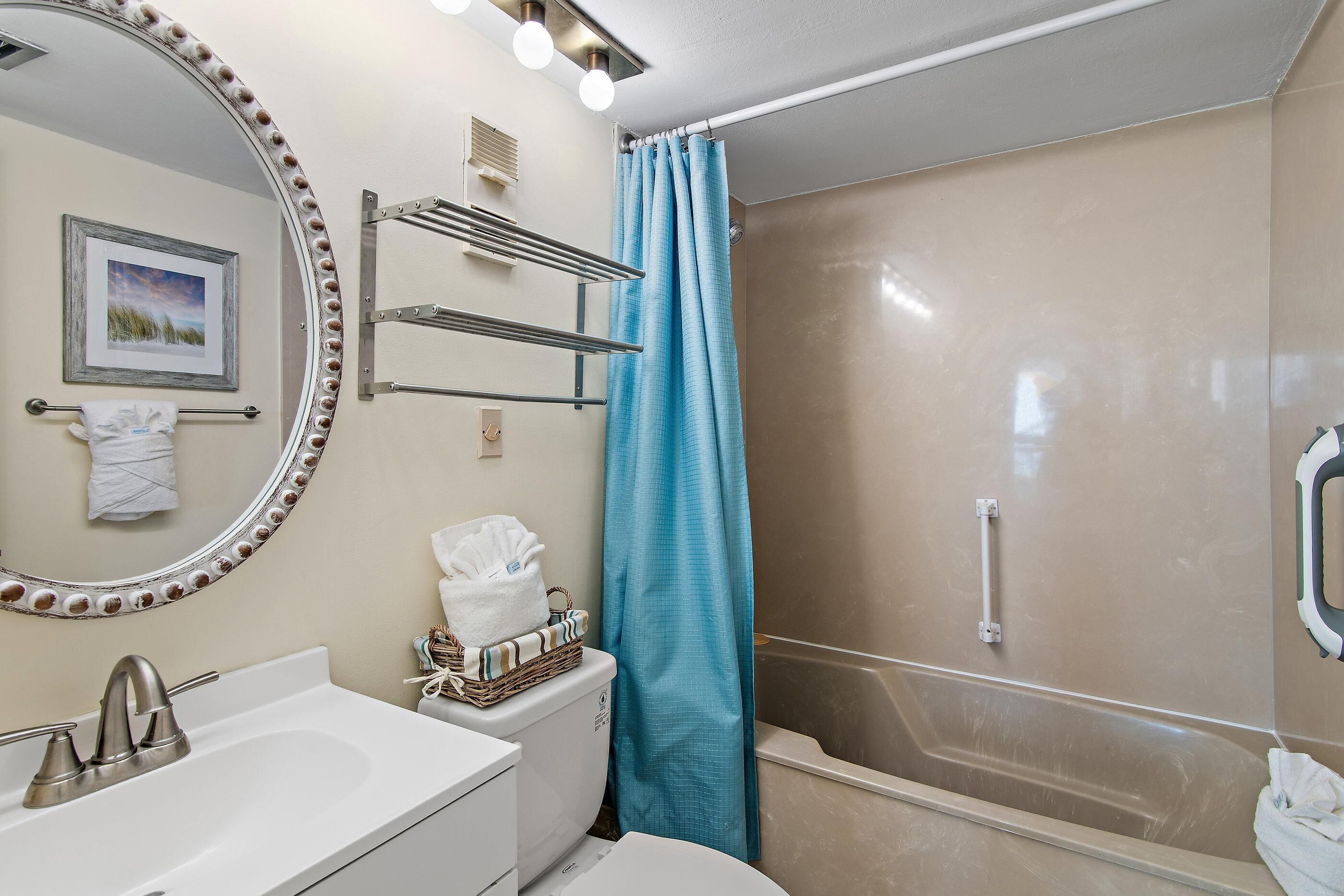 Un baño con lavamanos, espejo, toallero y zona de ducha.