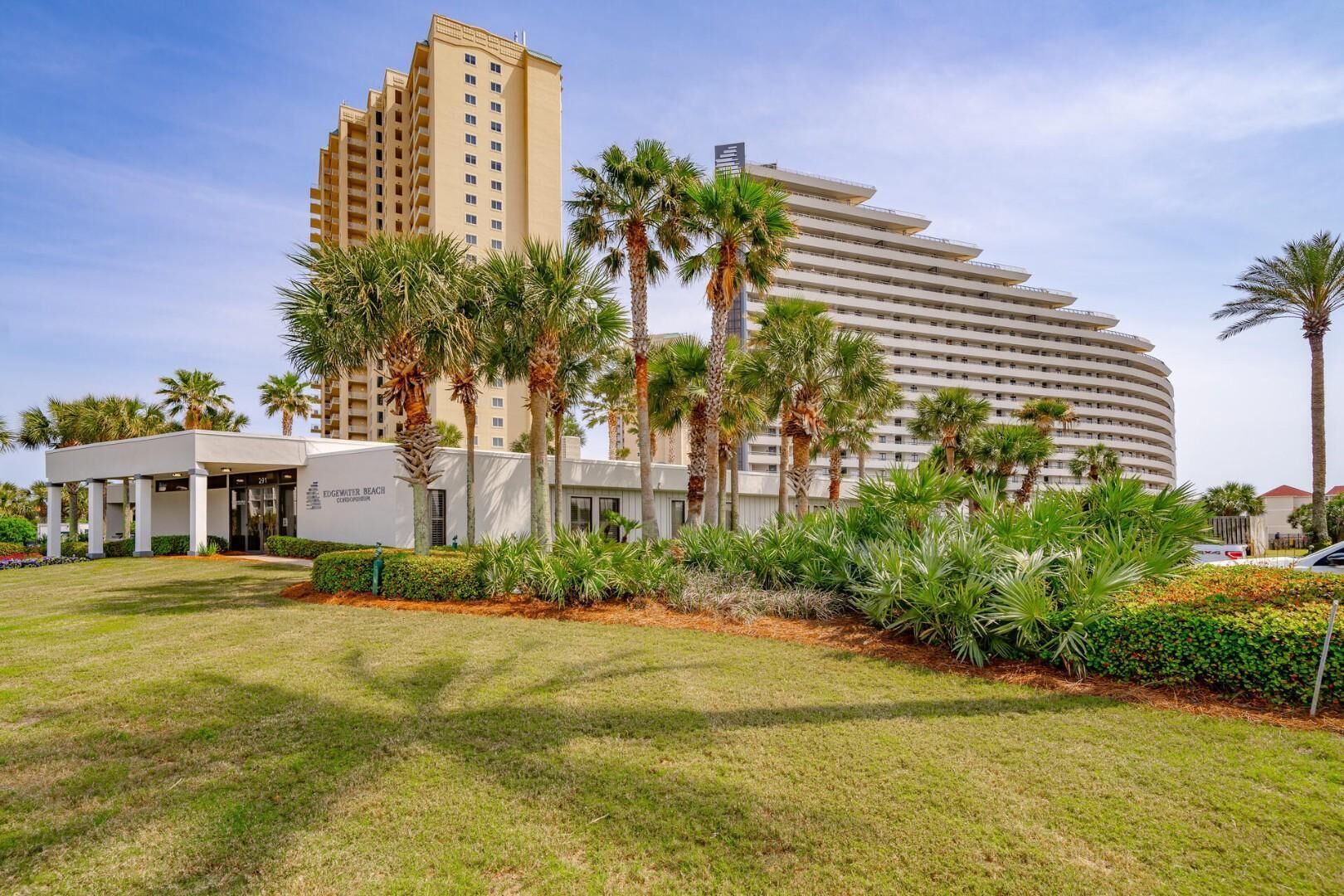 Un hôtel au design moderne, caractérisé par un bâtiment aux lignes courbes et un bâtiment séparé abritant l’entrée, portant l’inscription « EDGEMORE BEACH CONDOMINIUM ».