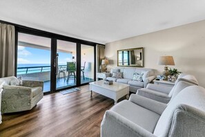 A modern hotel room with a balcony, a sofa set, a coffee table, and a lamp. - Edgewater #1400 - Emerald View (Miramar Beach)