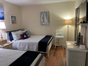 A hotel room with two beds, a chair, a small table, and a lamp. - Edgewater #1400 - Emerald View (Miramar Beach)