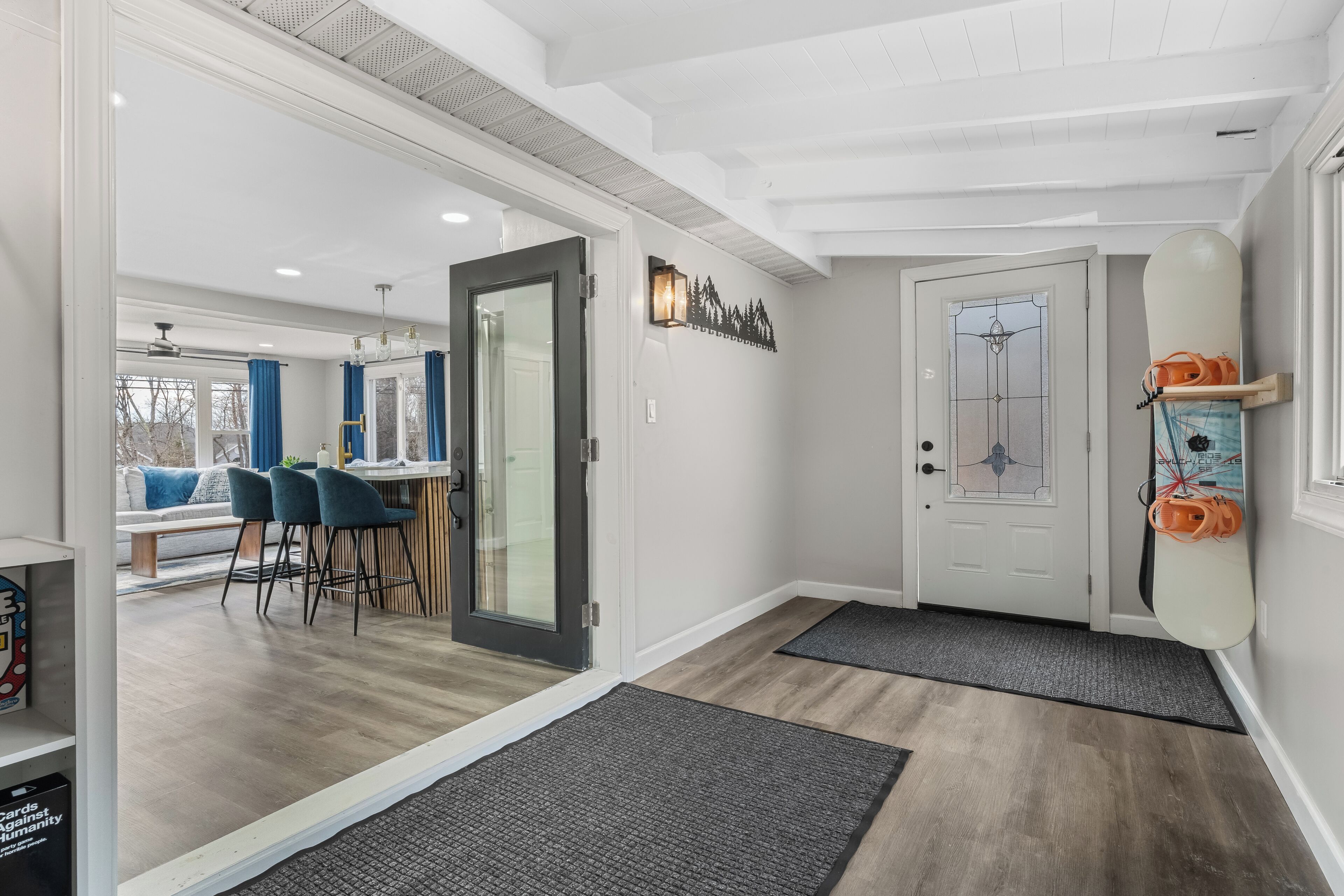 Un intérieur moderne avec un plancher en bois, une porte en verre donnant sur un coin repas et une porte blanche agrémentée d’un panneau de verre décoratif.