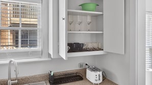 A kitchen with a built-in shelf holding glasses, a green bowl, and a toaster. - Museum & Med District Retreat 2BR + Parking (Houston)