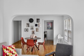 A modern dining area with a round table, red chairs, and a clock on the wall. - Museum & Med District Retreat 2BR + Parking (Houston)