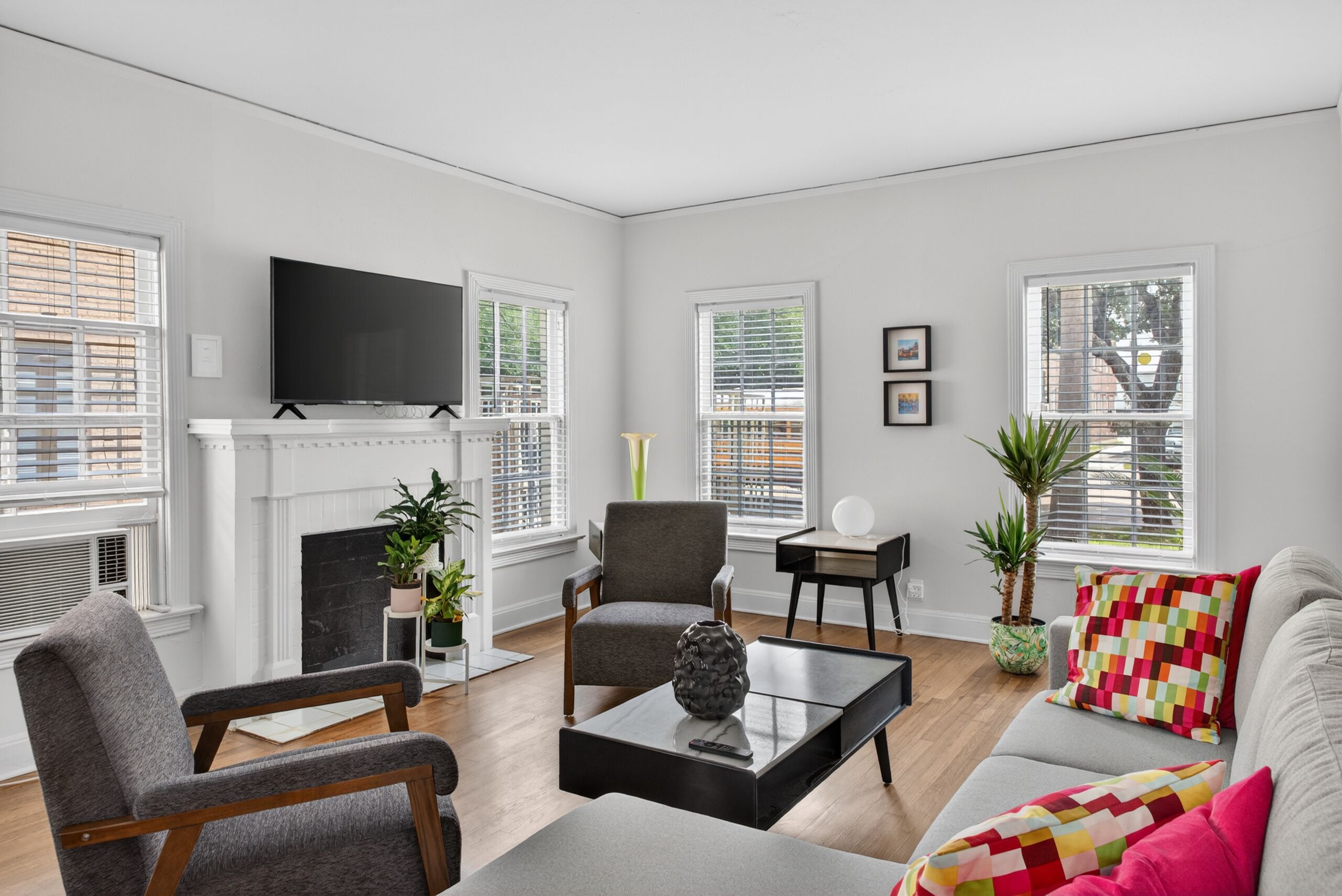 A modern living room with a fireplace, seating, and large windows.