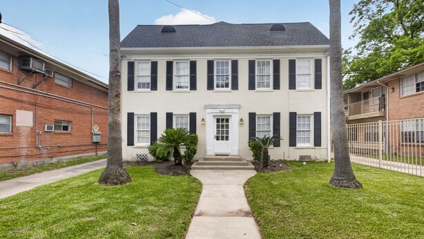 A two-story building with a central entrance, flanked by two palm trees. - Museum & Med District Retreat 2BR + Parking (Houston)