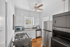 A compact kitchen with white cabinets, a gas stove, a stainless steel refrigerator, and a built-in oven. - Museum & Med District Retreat 2BR + Parking (Houston)