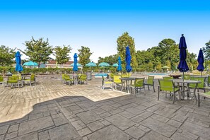 An outdoor patio area with stone flooring, green and yellow chairs, and blue umbrellas. - Ocean View Beach Club - 18 Middlesex Dr (Ocean View)