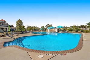 Ein großer, klarer Swimmingpool mit Tiefenmarkierung von etwa 1,45 Meter, umgeben von Liegestühlen und Sonnenschirmen.