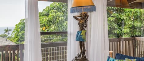 A room with a view of the ocean, a statue, a table, and a couch.