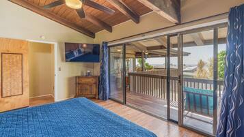 Ein Schlafzimmer mit einem großen Bett, einem Fernseher und einer Glastür zum Balkon mit Blick.