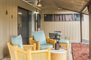 A covered outdoor seating area with wicker furniture and a table.