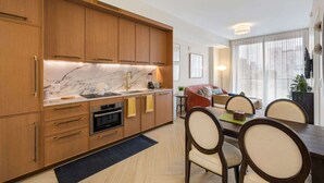 A modern kitchen with wooden cabinets, a marble countertop, and a dining area with a table and chairs. - 1BR 1BA Miami Apt Pool Ocean Views Ideal for 3 (Miami)