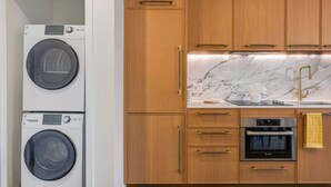 A kitchen with wooden cabinets, a Bosch oven, a sink with a marble countertop, and stacked washing machines. - 1BR 1BA Miami Apt Pool Ocean Views Ideal for 3 (Miami)