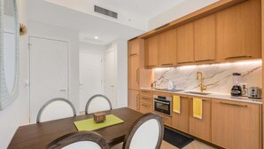 A modern kitchen with wooden cabinets, a marble countertop, and a built-in oven. - 1BR 1BA Miami Apt Pool Ocean Views Ideal for 3 (Miami)