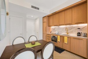 A modern kitchen with wooden cabinets, a marble countertop, and a built-in oven. - 1BR 1BA Miami Apt Pool Ocean Views Ideal for 3 (Miami)