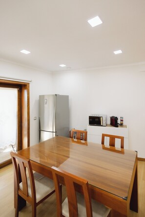 A modern kitchen with a built-in microwave, a refrigerator, and a coffee machine on a small countertop. - COUTO REFUGE (Cabeceiras de Basto)