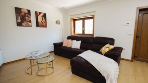 Ein Wohnzimmer mit einem dunkelbraunen Sofa, einem Glastisch und zwei Bildern an der Wand.