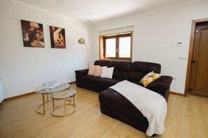 Ein Wohnzimmer mit einem dunkelbraunen Sofa, einem Glastisch und zwei Bildern an der Wand.
