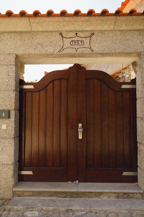 Een grote houten poort met een metalen slot, geplaatst in een stenen boogvormige opening, met een plaquette erboven.