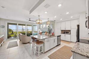 A modern kitchen with a large island, white cabinetry, and a view of the outdoors. - Water View Escape- Minutes to Anna Maria Island Beaches-Gated Community of One Particular Harbour (Bradenton)