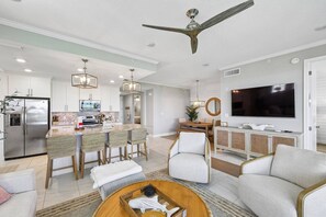 Eine moderne Küche mit integriertem Kühlschrank, Essbereich mit Stühlen, einem Fernseher und einem Deckenventilator.