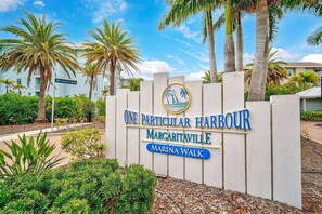 A sign for 'One Particular Harbour' in Margarita Walk, with palm trees and a clear sky in the background. - Water View Escape- Minutes to Anna Maria Island Beaches-Gated Community of One Particular Harbour (Bradenton)