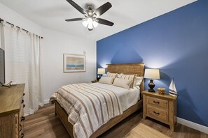 A bedroom with a bed, nightstands, a ceiling fan, a framed picture, and a sailboat decoration. - Water View Escape- Minutes to Anna Maria Island Beaches-Gated Community of One Particular Harbour (Bradenton)