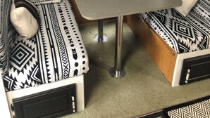 Ein gemütlicher Wohnbereich mit Sofa, kleinem Tisch, Vorhängen und gemusterten Kissen.