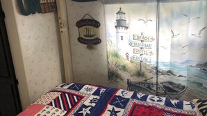 Ein Zimmer mit einem Bett, einer Wand mit maritimer Dekoration und einem Fenster mit Meerblick.