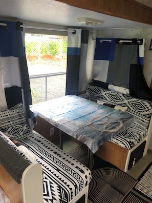 A compact room with a bed, a table, and a bench. - Quaint 1-bedroom 30' 5th wheel in pleasant Lake Goodwin for relaxing (Stanwood)