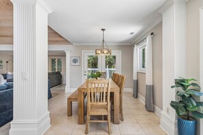 A dining area with a wooden table and chairs, a hanging light fixture, and a view of the living room through an open door. - Private Pool | 3BR Retreat + FREE Daily Activities (Hilton Head Island)