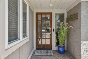 A wooden front door with a glass panel, a welcome mat, and a potted plant. - Private Pool | 3BR Retreat + FREE Daily Activities (Hilton Head Island)