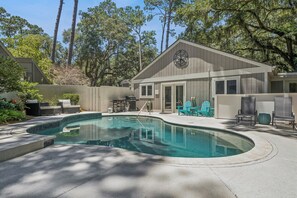 A pool area with a house, outdoor seating, and a compass sign. - Private Pool | 3BR Retreat + FREE Daily Activities (Hilton Head Island)