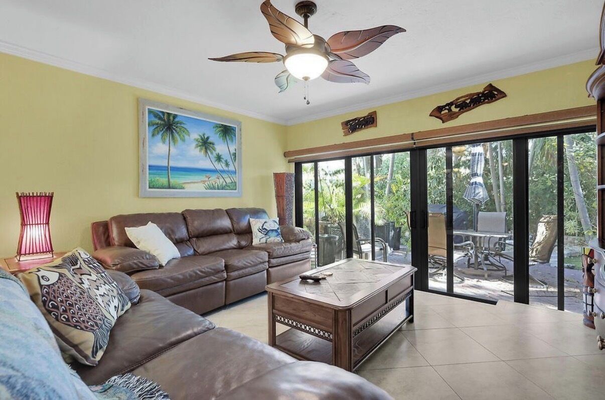 A living room with a brown leather sofa, a wooden coffee table, and a ceiling fan.