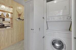 Ein Waschraum mit einer Frontlader-Waschmaschine und einem Holzschrank mit Dekorationselementen.