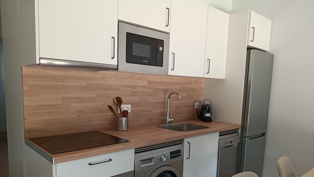 A compact kitchen with a microwave, oven, washing machine, and a refrigerator. - The Rooftop Apartment A (Basauri)