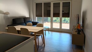 A modern living space with a dining area, a sofa, and a balcony with large windows. - The Rooftop Apartment A (Basauri)