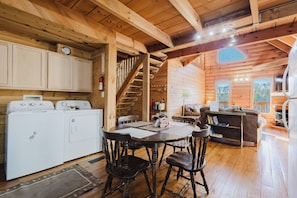 A wooden cabin interior with a kitchen, dining area, and living space. - Cliffline Sunset Views with New Hot Tub, Pet Friendly (Zoe)