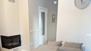 A bedroom with a bed, a wall clock, and a fireplace.