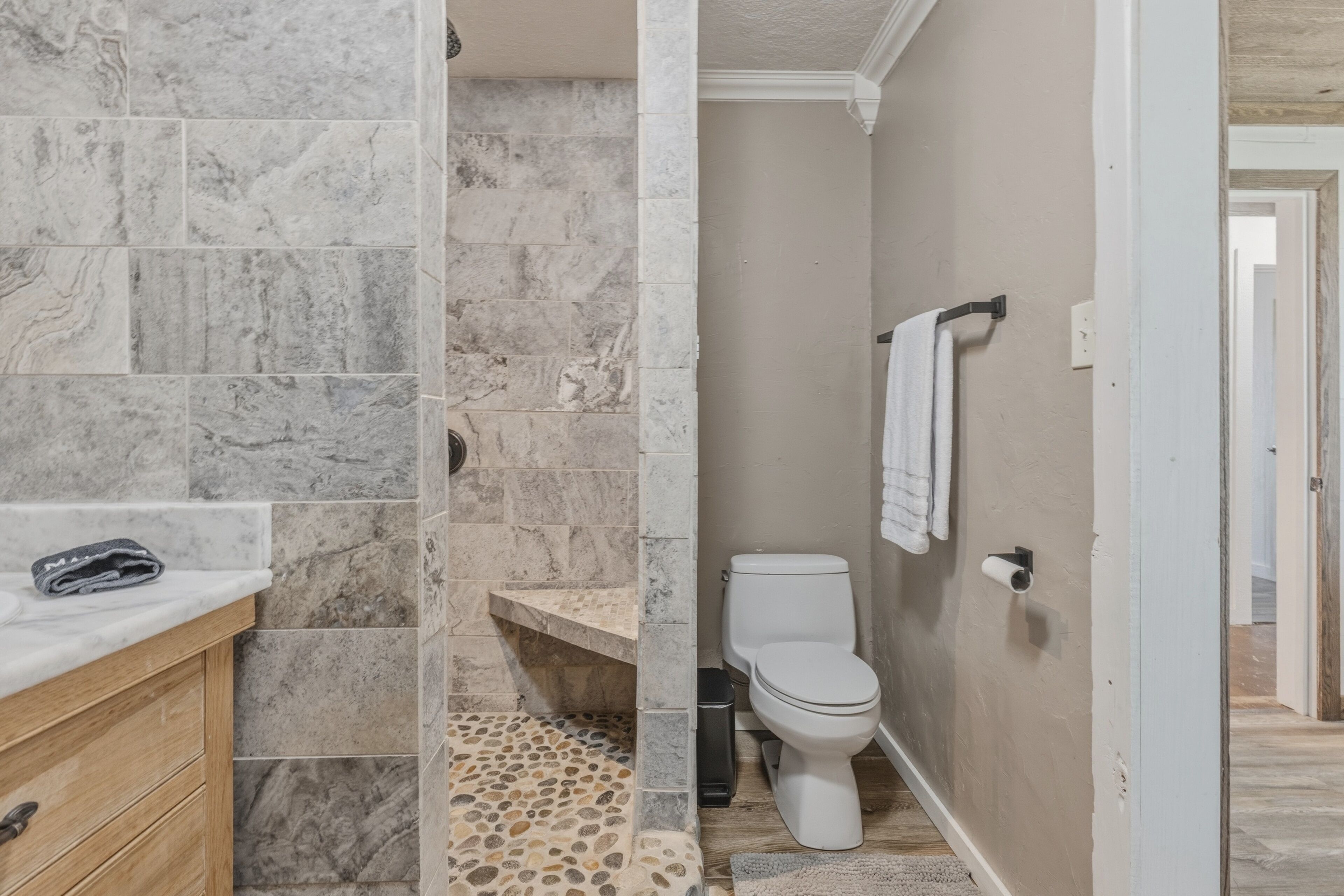 A bathroom with a marble vanity, a toilet, and a shower area.