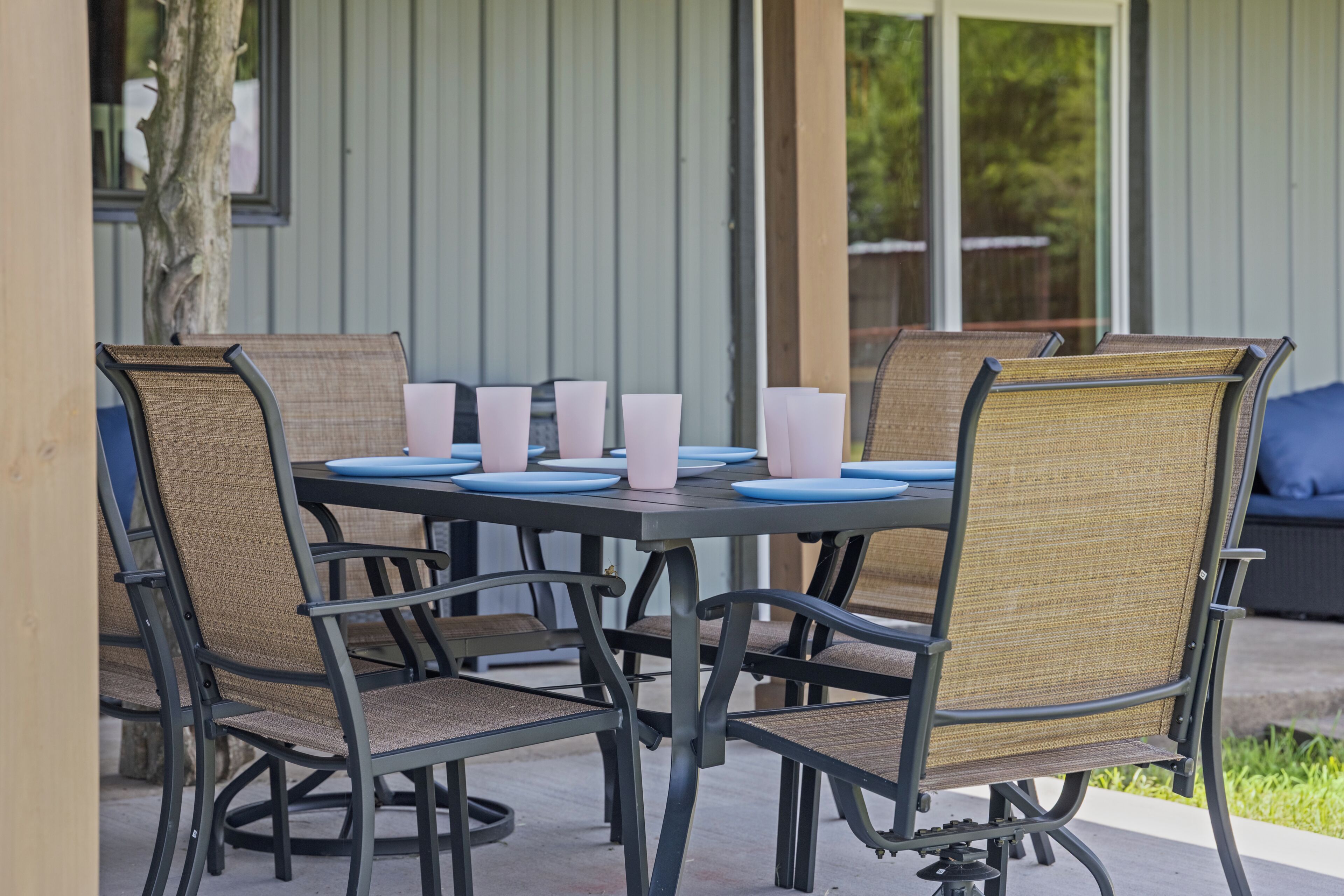 A round table with six chairs, each with a woven seat and backrest, and a black metal frame.
