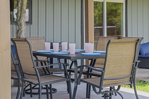A round table with six chairs, each with a woven seat and backrest, and a black metal frame.