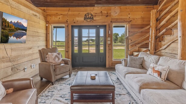 A wooden cabin interior with a sofa, armchair, and a coffee table.