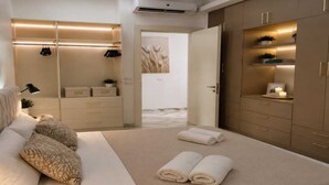 A modern bedroom with a large bed, a bedside table, a wardrobe, and a mirror. - Gold Apartment NAAMABAY near the beach with a free shuttle (Sharm el-Sheikh)