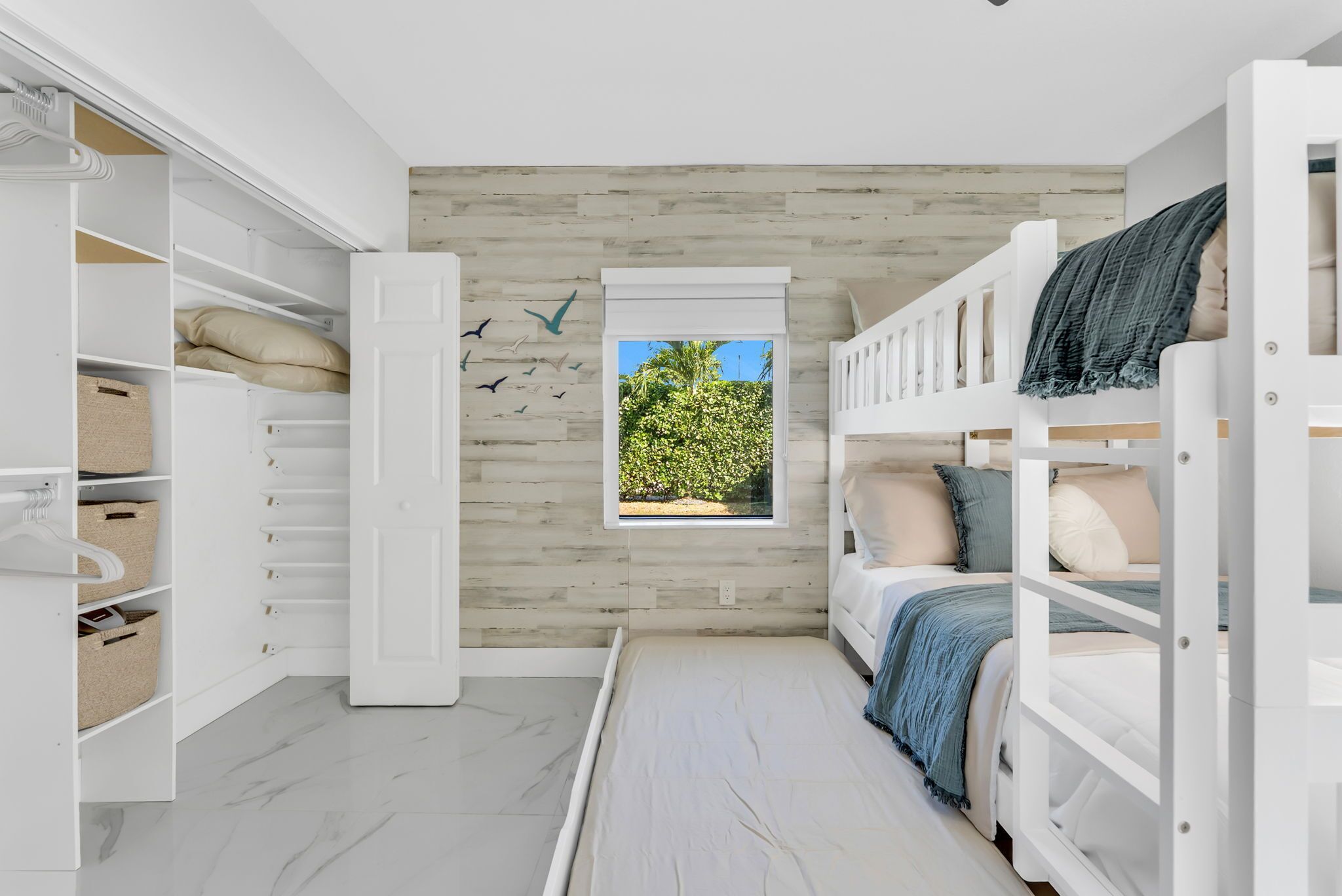 Une chambre avec un lit superposé, une armoire et une fenêtre donnant sur un paysage verdoyant.